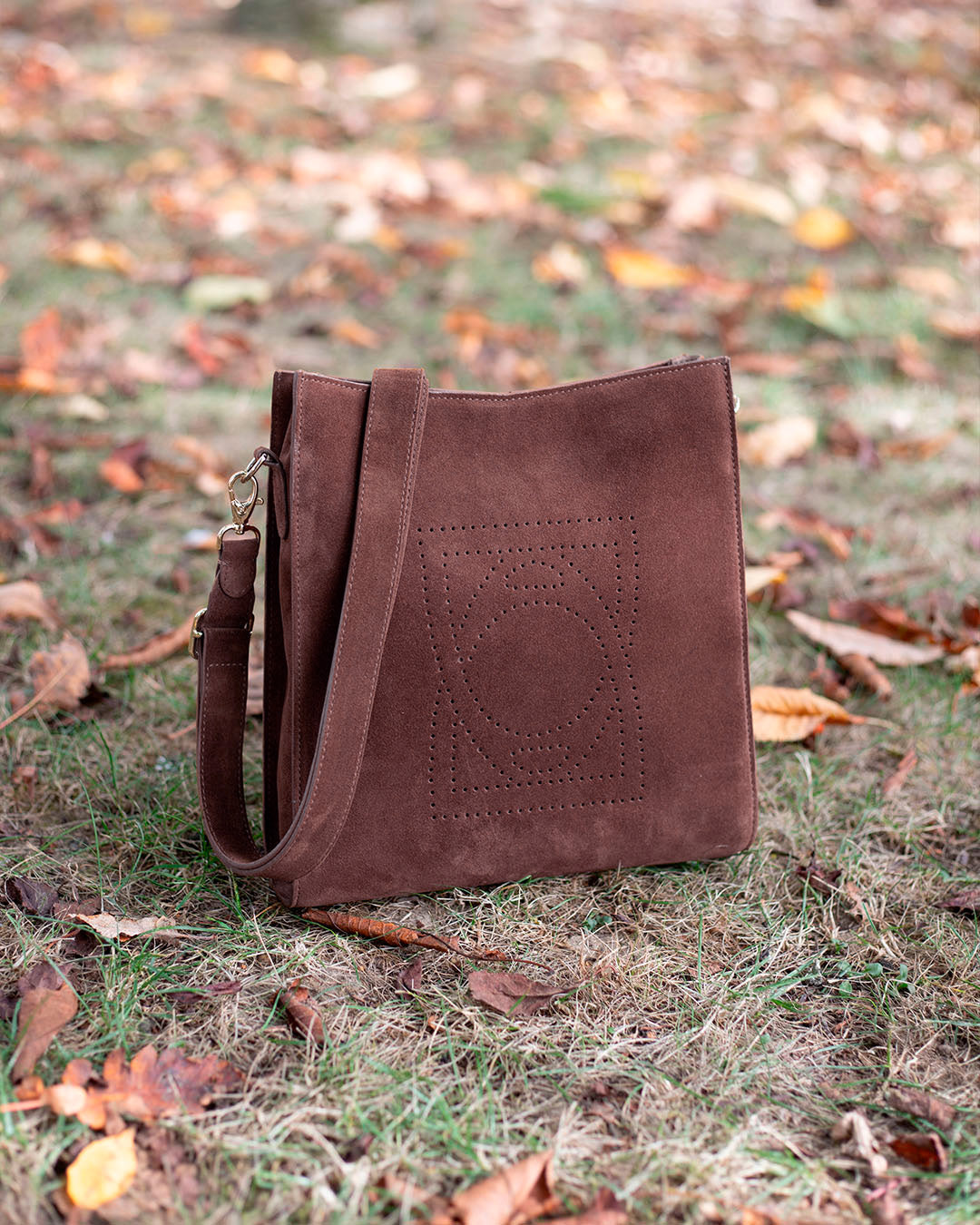Le sac Mini Étrivière Renouard en cuir veau velours acajou et sa bandoulière cuir, vu en ambiance.