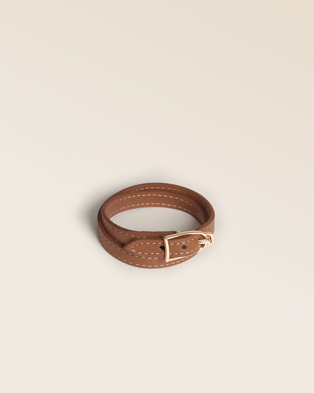 Notre bracelet Derby Renouard en cuir vintage camel et accessoire doré, vu de quart en studio.
