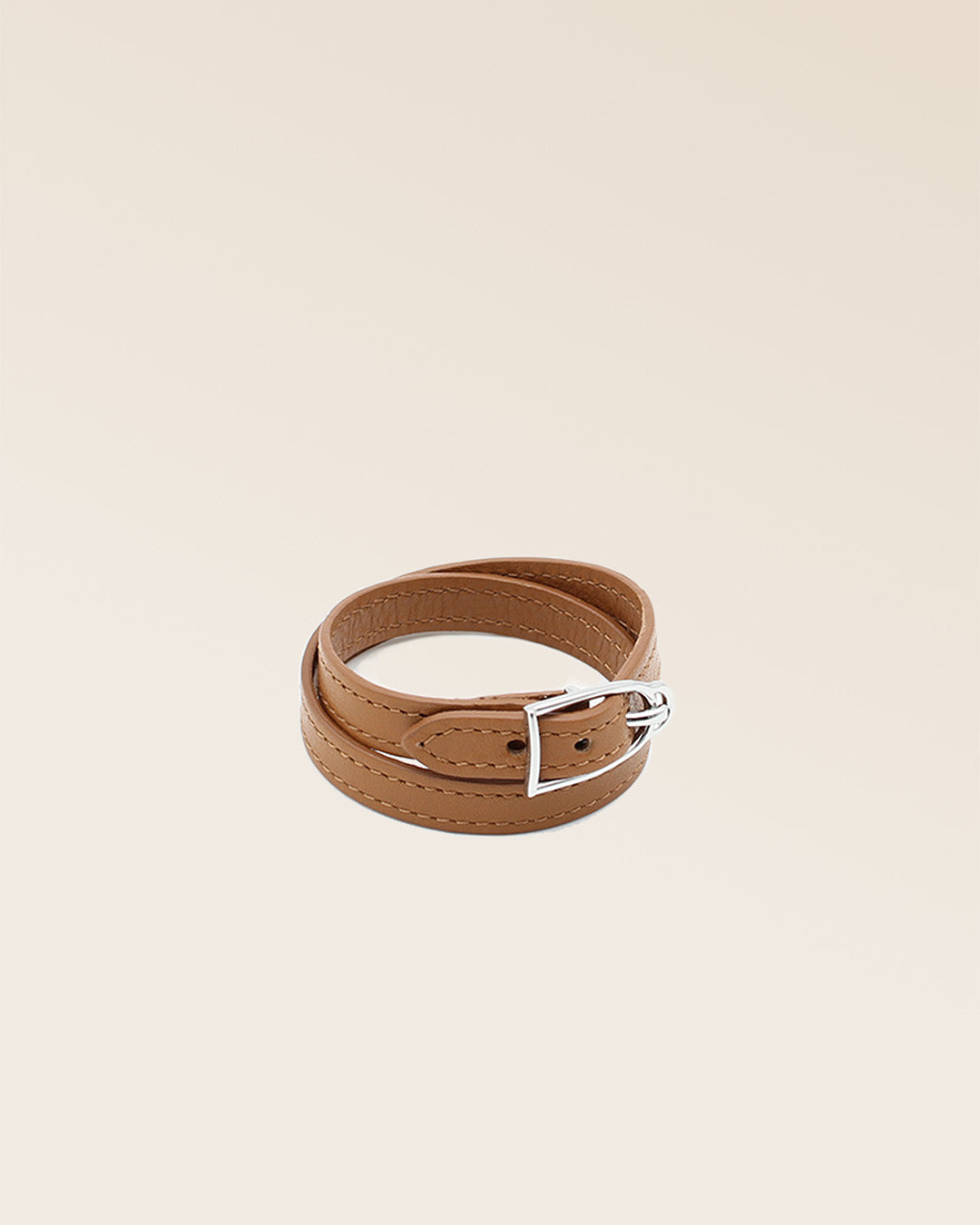 Notre bracelet Derby Renouard en cuir vintage camel et accessoire nickelé, vu de quart en studio.