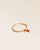 Notre bracelet Jumping Renouard en cuir d'agneau camel et pompon orange, vu de quart en studio.