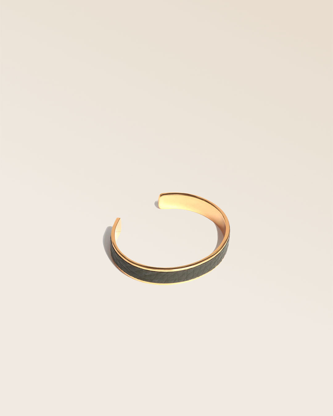 Notre bracelet Pacôme doré en cuir façon vigogne kaki vu de quart en studio.
