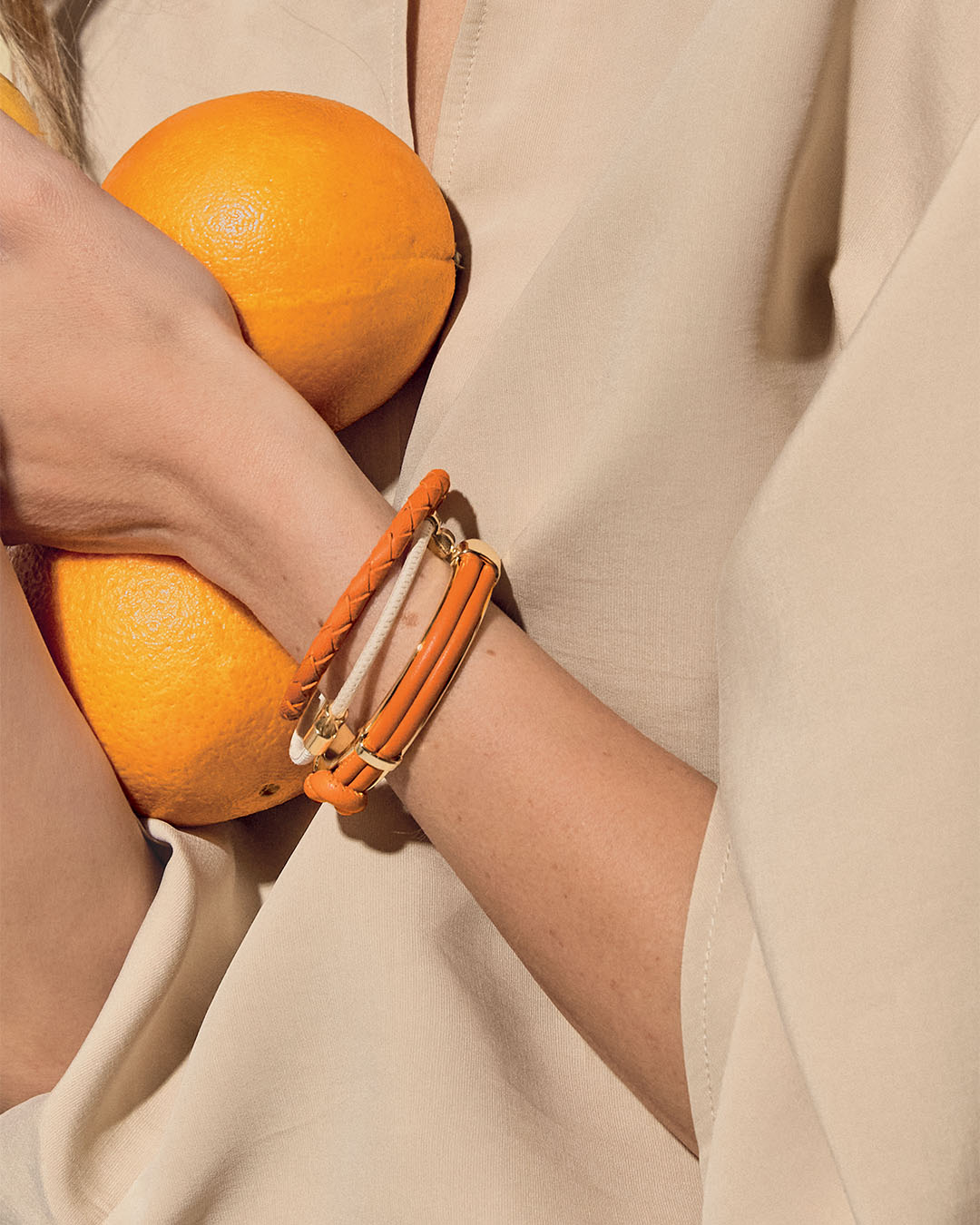 Nos bracelets Mohican, Mia et Doris Renouard en cuir d'agneau orange et craie, vus portés par notre mannequin. 