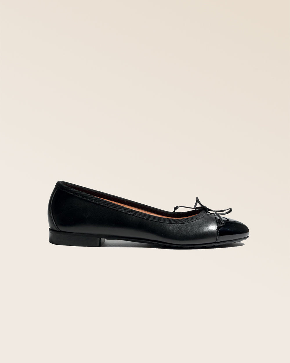 Nos ballerines Friandise Renouard en cuir lisse noir et bout vernis, vues de côté en studio.