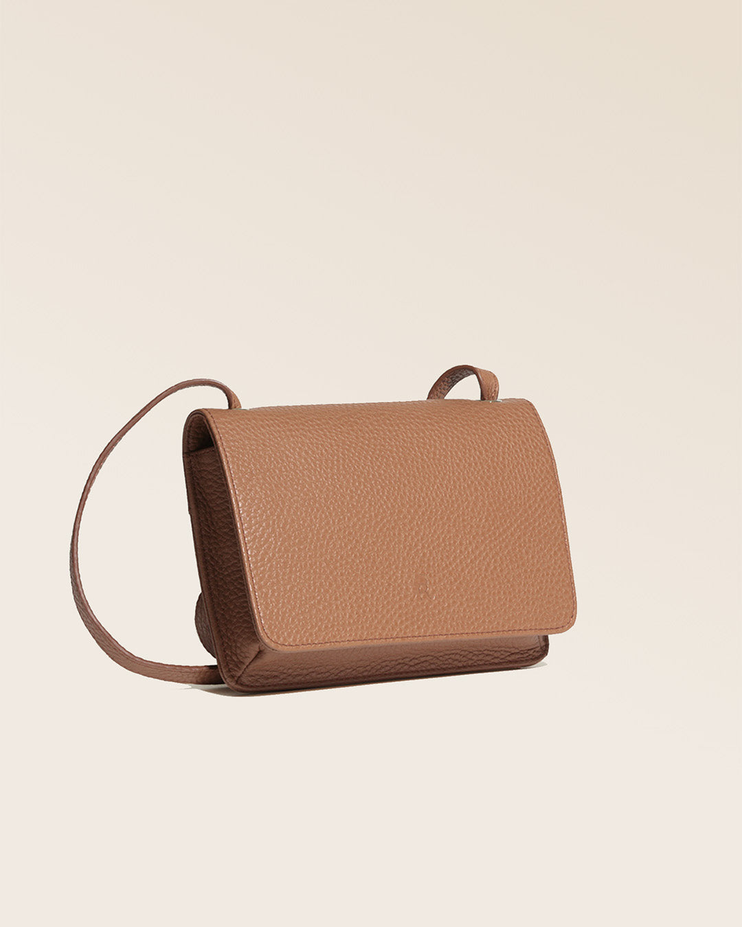 Notre pochette Fréhel en cuir façon vigogne fauve vue de quart en studio.