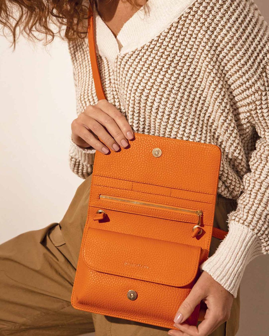 Notre pochette Fréhel en cuir façon vigogne orange vue de face portée par notre mannequin.