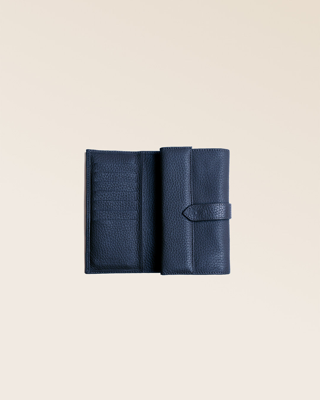 Notre porte-monnaie Adèle en cuir façon vigogne bleu marine vu ouvert en studio.