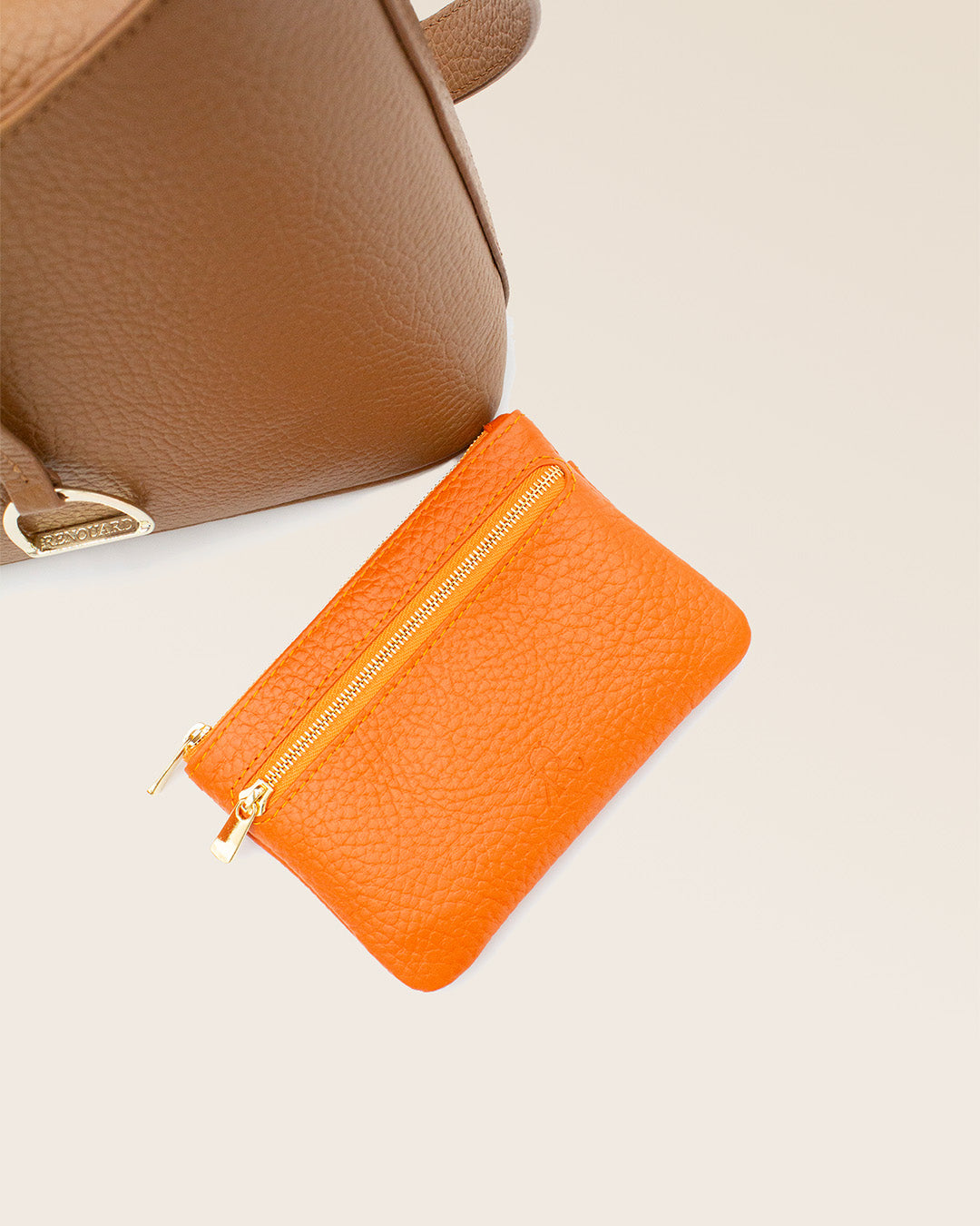 Notre porte-monnaie Capucine Renouard en cuir façon vigogne orange vu en ambiance en studio.