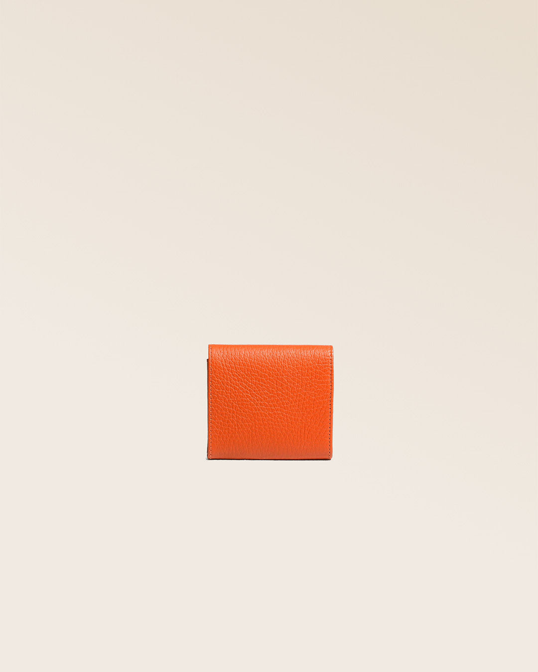 Notre porte-monnaie Castel en cuir façon vigogne orange vu de dos en studio.
