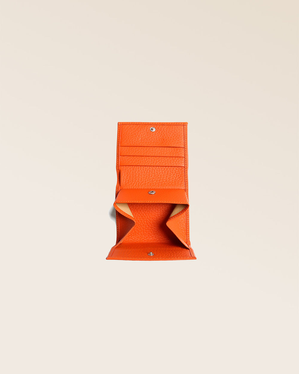 Notre porte-monnaie Castel en cuir façon vigogne orange vu ouvert en studio.