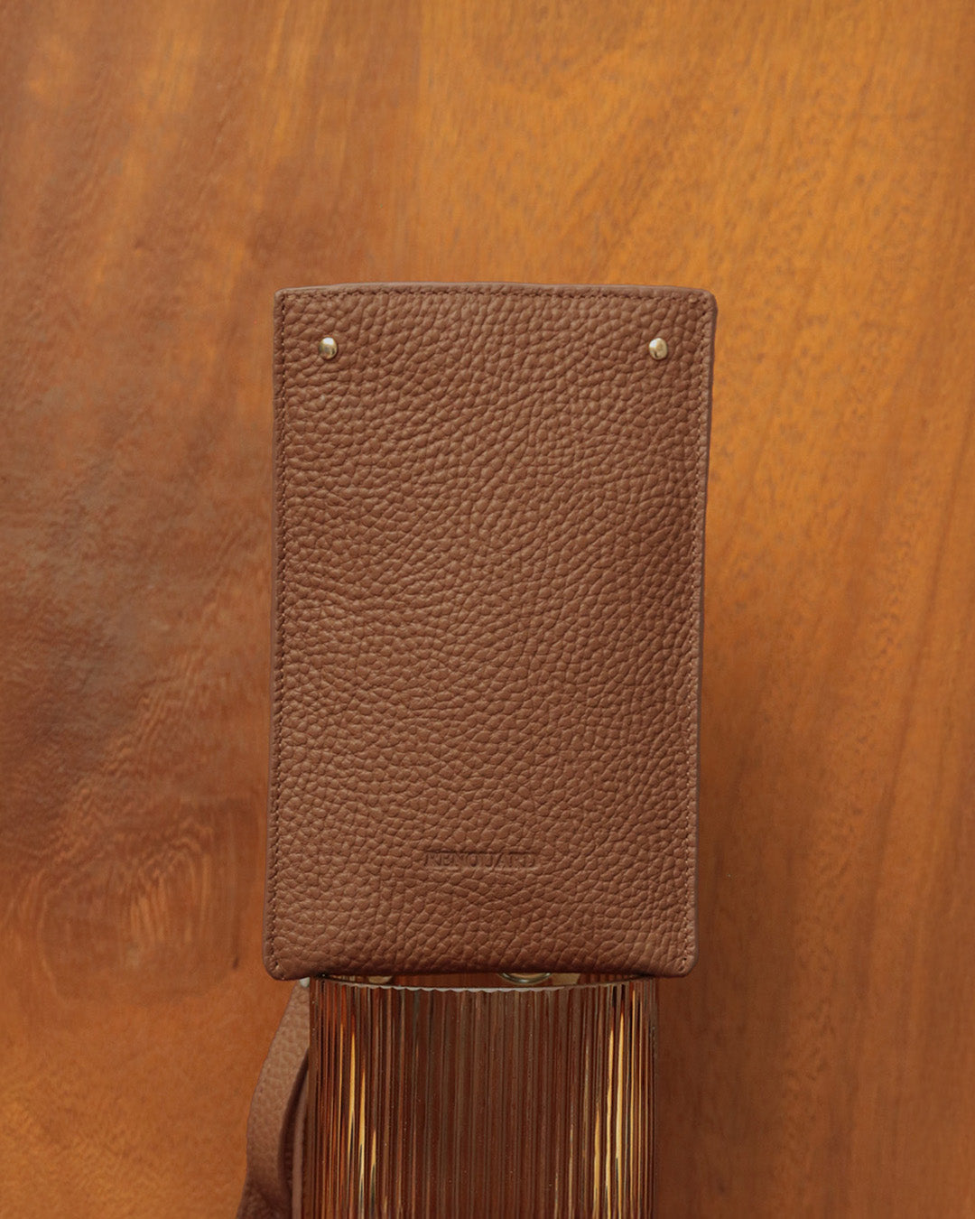 Notre pochette téléphone Renouard en cuir façon vigogne fauve, vue de face en ambiance.