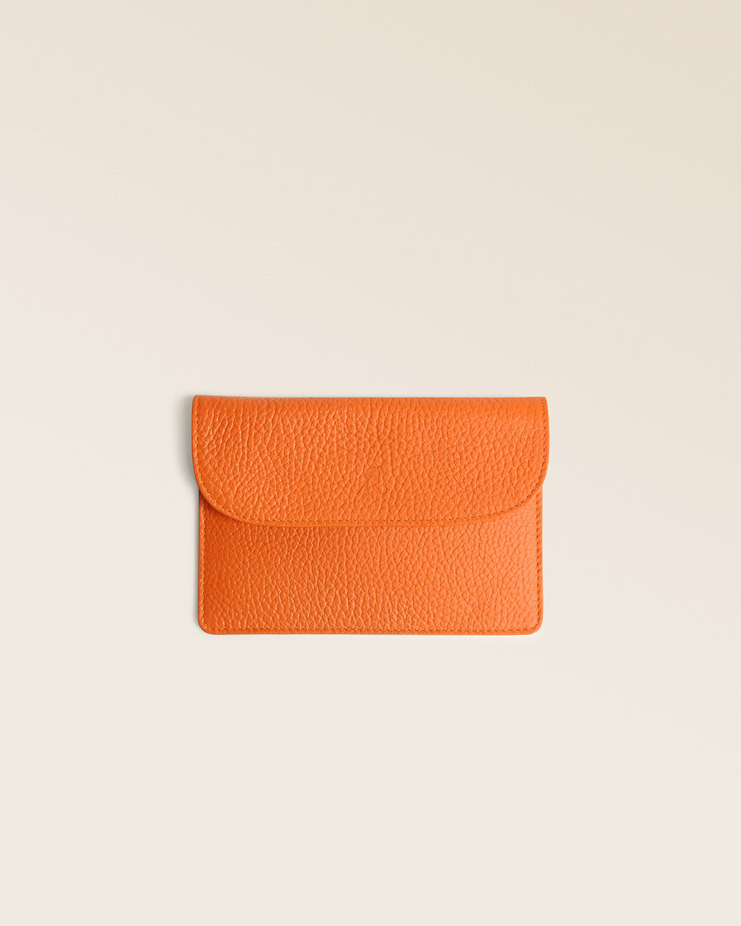 Notre porte-papiers Aurore Renouard en cuir façon vigogne orange, vu de face en studio.