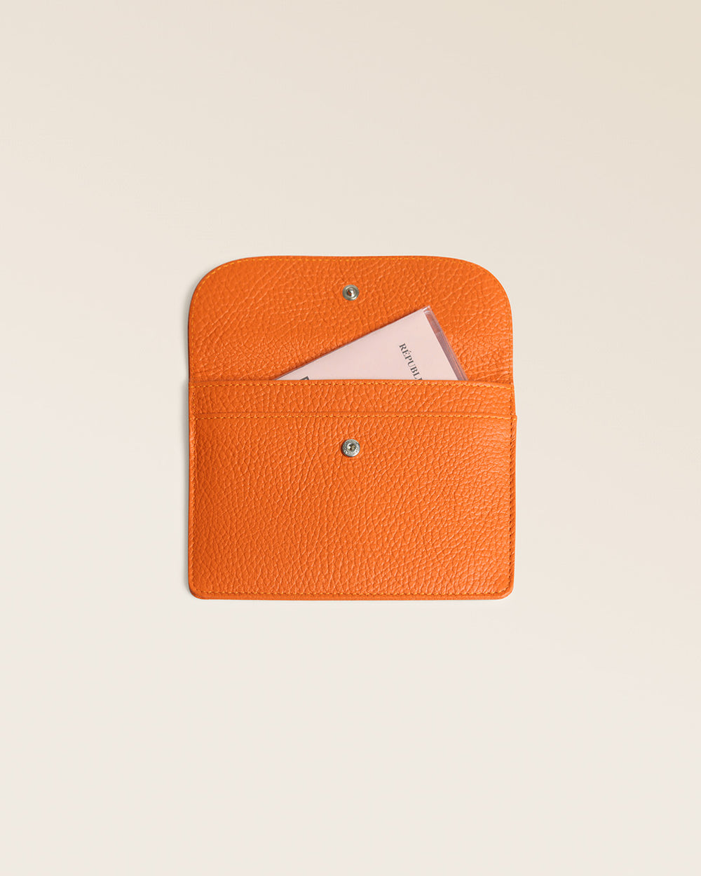 Notre porte-papiers Aurore Renouard en cuir façon vigogne orange, vu de face ouvert en studio.