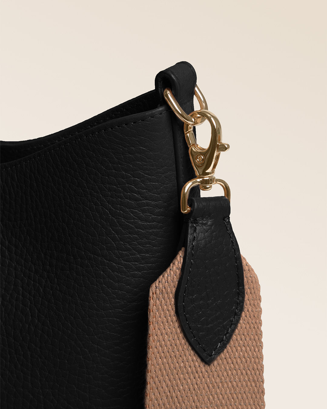 Notre sac Cob Renouard dans sa version Petit modèle, en cuir façon vigogne noir, accessoires dorés et bandoulière coton ; vu de près en studio.
