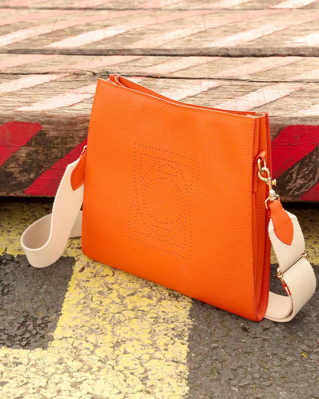 Notre sac Étrivière petit modèle en cuir façon vigogne orange vu de face en ambiance.